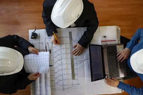 A group of people sitting at a table with papers and laptops.