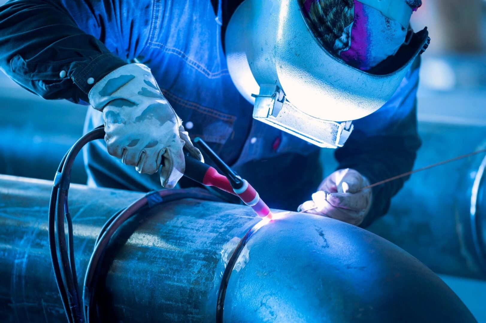 A person welding in the dark with blue light.