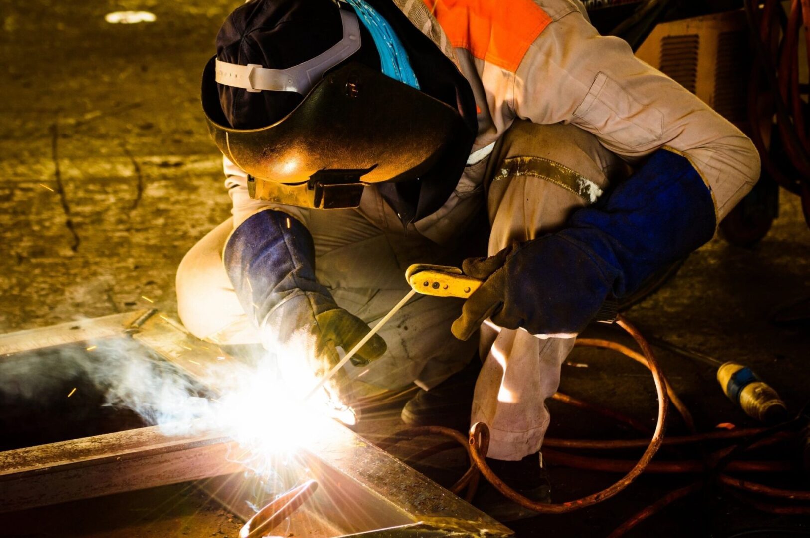 A man welding metal with an electric welder.