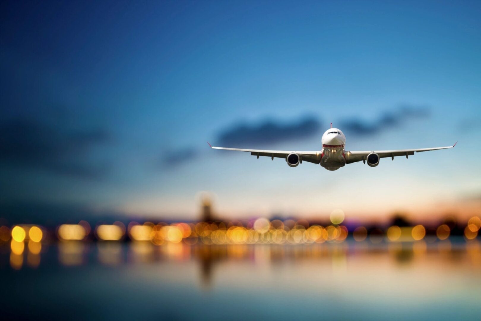 A plane flying over the water at night.