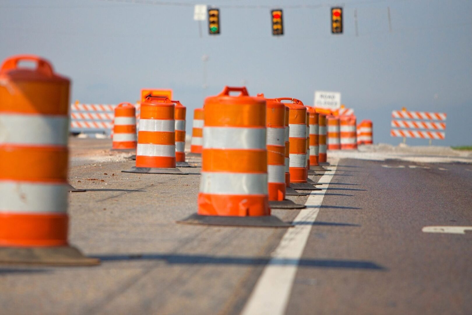 A bunch of orange and white barrels on the side of the road