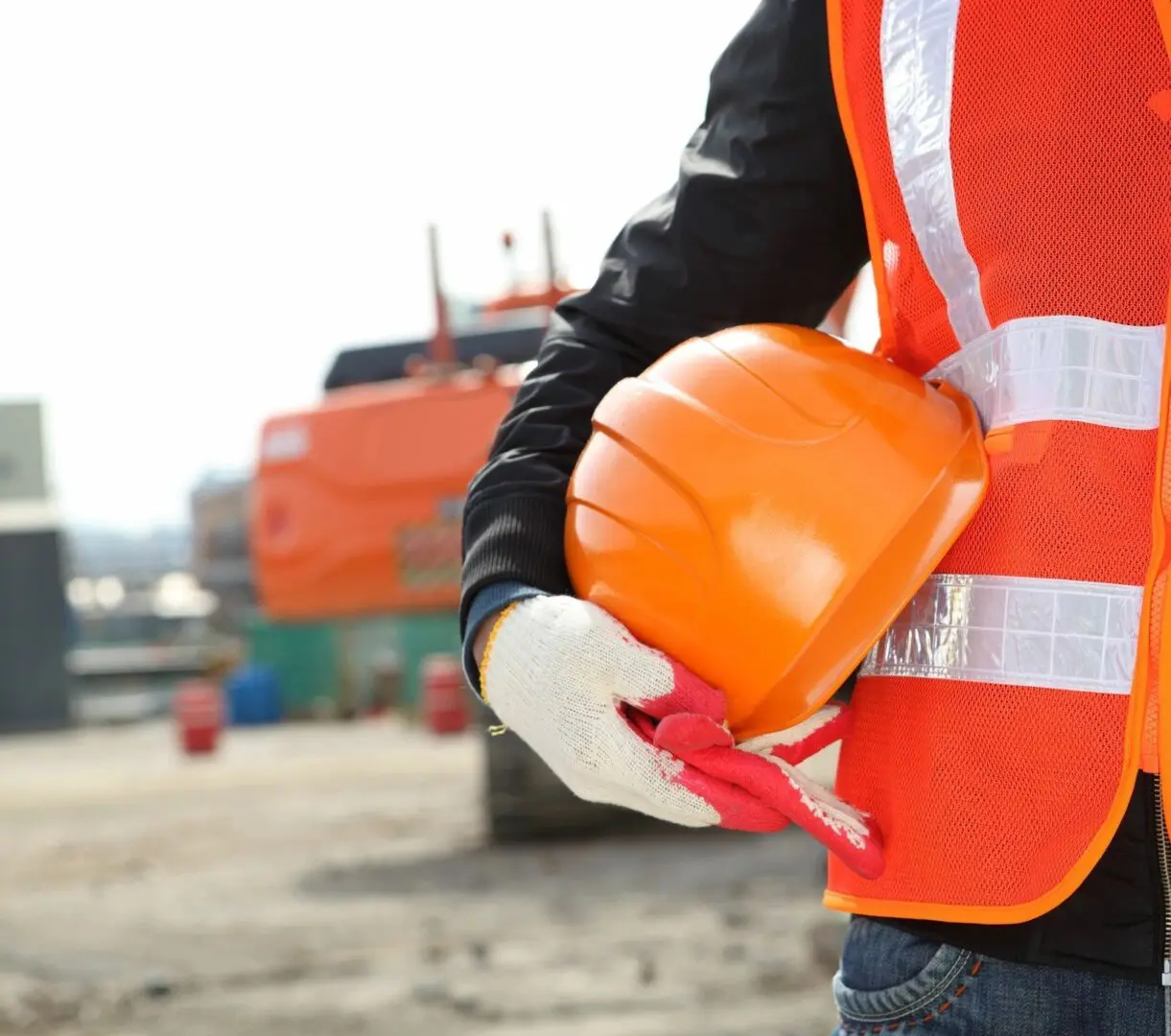 A construction worker holding his helmet and gloves.