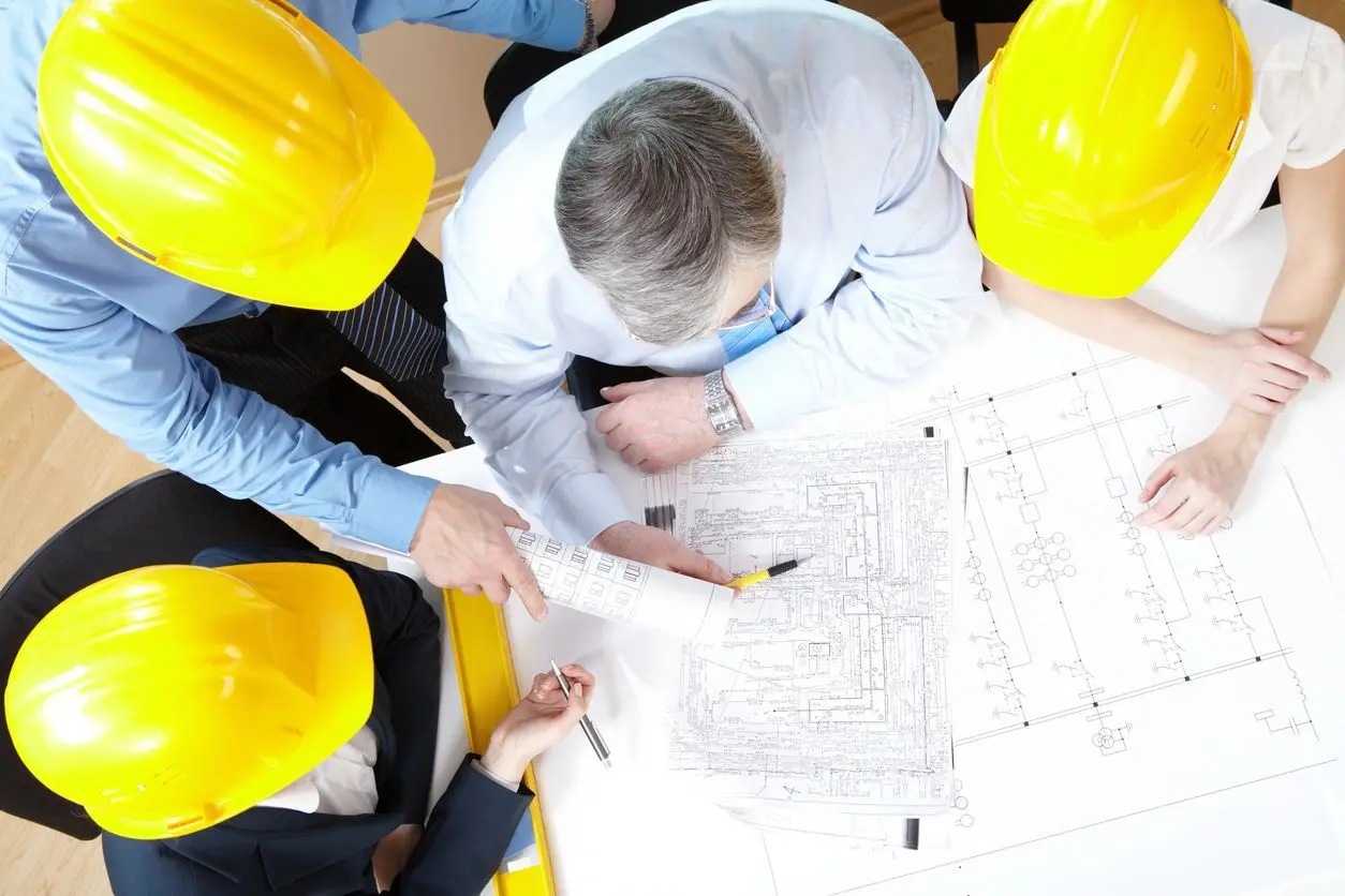 A group of people with hard hats on looking at plans.